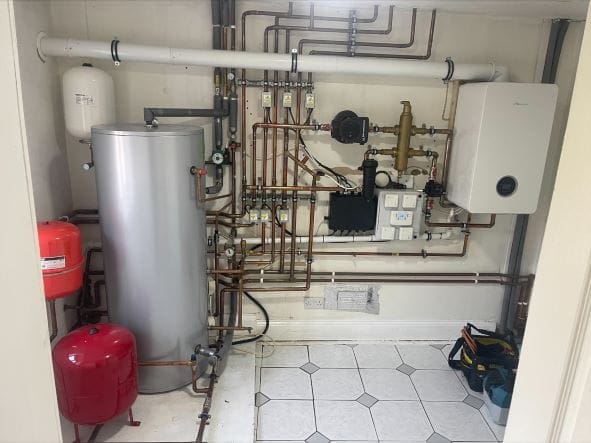 Heating engineer checking radiators and smart controls in a Poringland family home