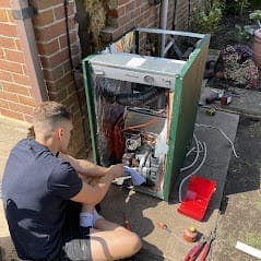 Oil boiler installation engineer working on an outdoor oil boiler for a home heating system