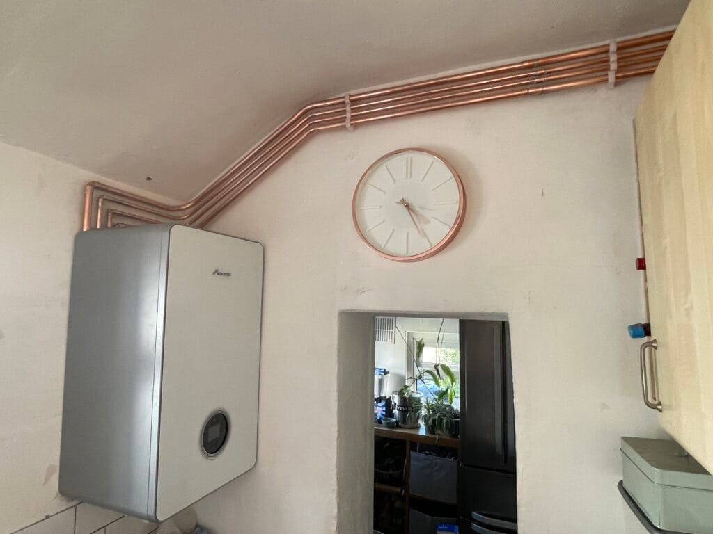 Worcester Bosch gas boiler installation with exposed copper pipework running neatly along the wall above a doorway