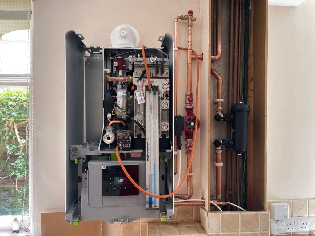 Gas boiler service with casing removed, flue gas analyser connected and copper pipework visible