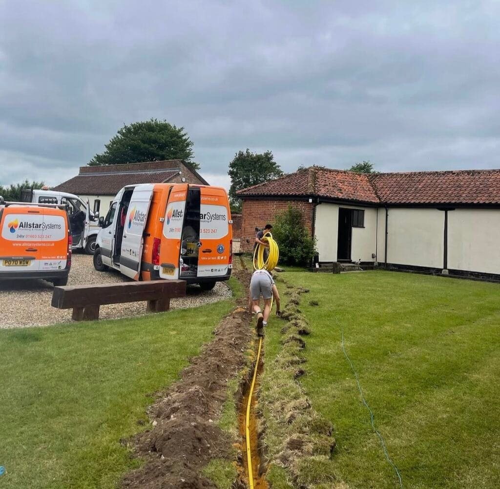 Allstar Systems engineers installing underground gas pipework across a garden with company vans on site