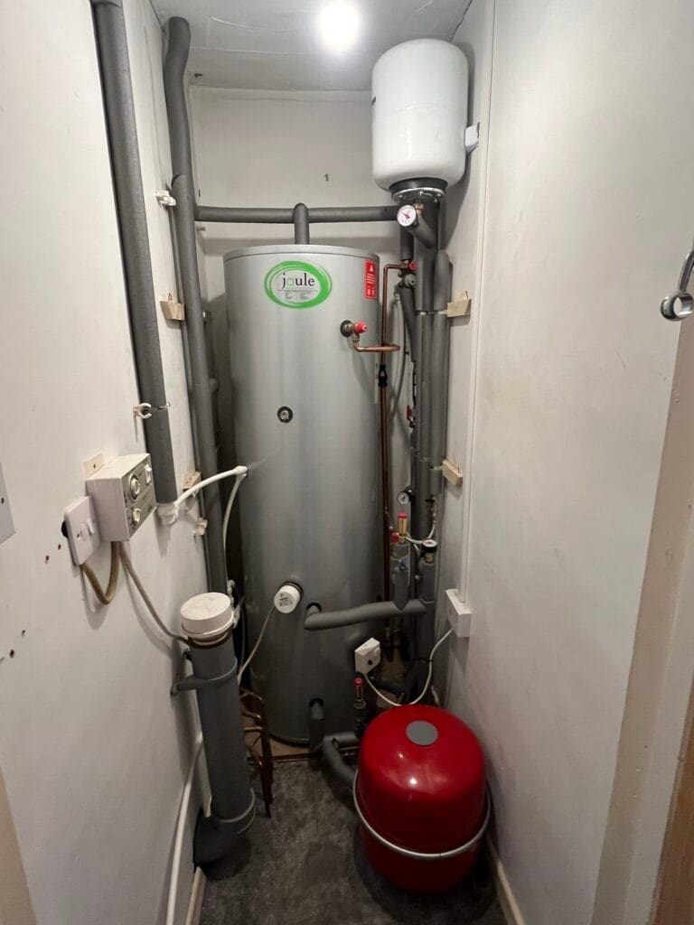 Moving Into A Home In Downham Market? Plumbing And Heating Checks To Make First | Allstar Systems Ltd Hot water cylinder with expansion vessel, pipework and heating controls in a domestic airing cupboard
