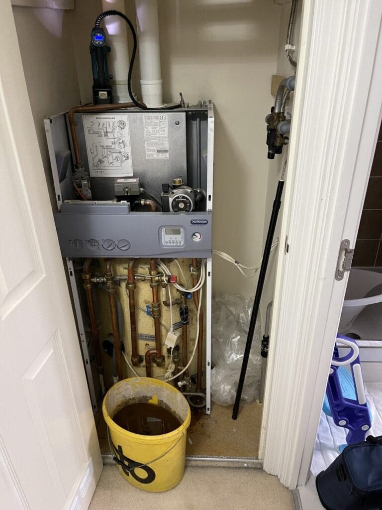 Gas boiler service with casing removed, internal components exposed and engineer testing equipment in place