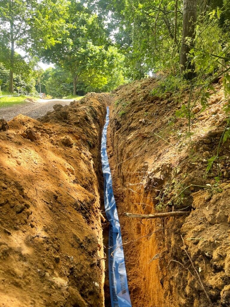 Underground water main pipe installed in a deep trench during external plumbing works in Norfolk